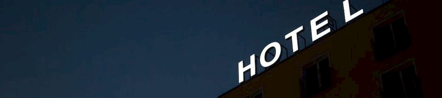A building's facade is visible with illuminated letters partially spelling "HOTEL" against a dark sky.